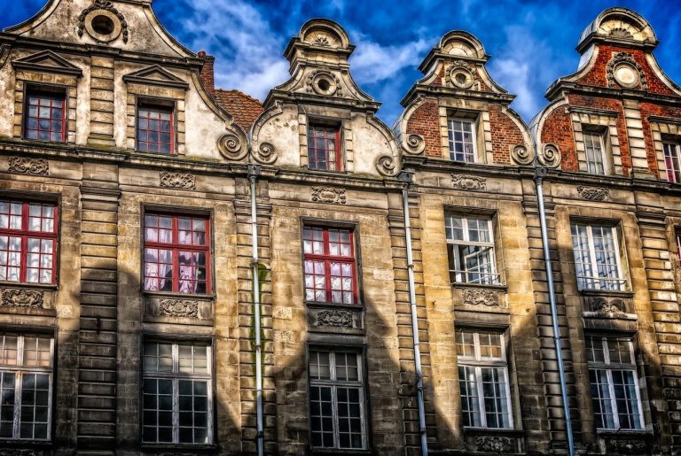 Homme en costume tenant une maison en miniature, utilisant une calculatrice.