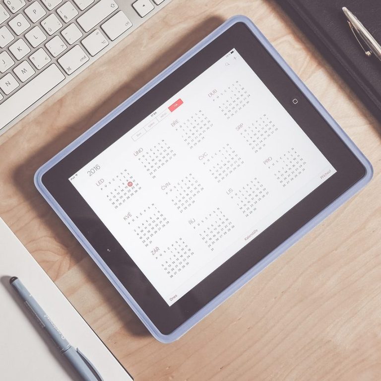 Calendrier numérique affiché sur une tablette, avec un bureau en arrière-plan.