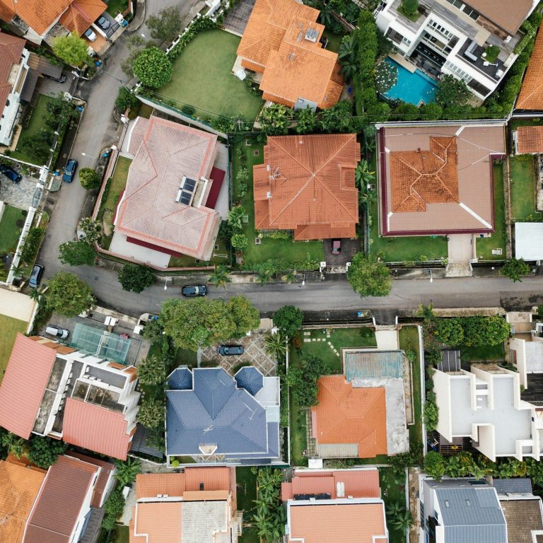 Vue aérienne de quartiers résidentiels avec maisons à toits multiples et verdure.
